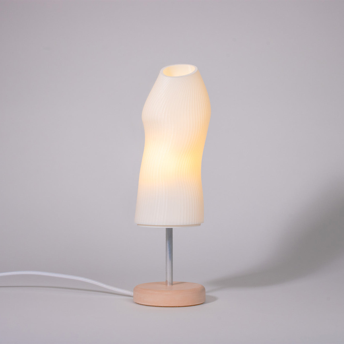 Ora Premium white sculptural table lamp with a terracota plaster base and a chrome rod photographed against a white background