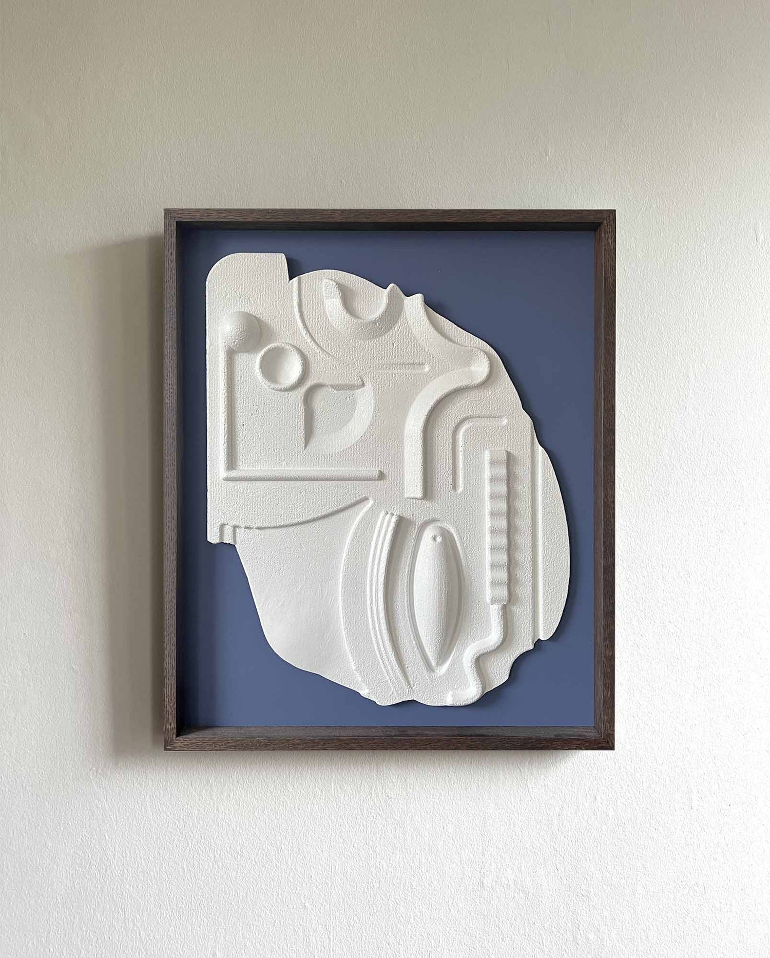 White relief artwork framed with mahogany stain and a blue background