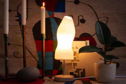 Ora premium table lamp styled with a Miro rug, a white sculpture, rubber plant and candles