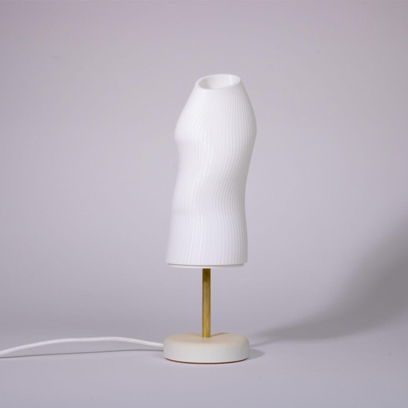 Ora Premium white sculptural table lamp with plaster base and brass rod photographed against a white background