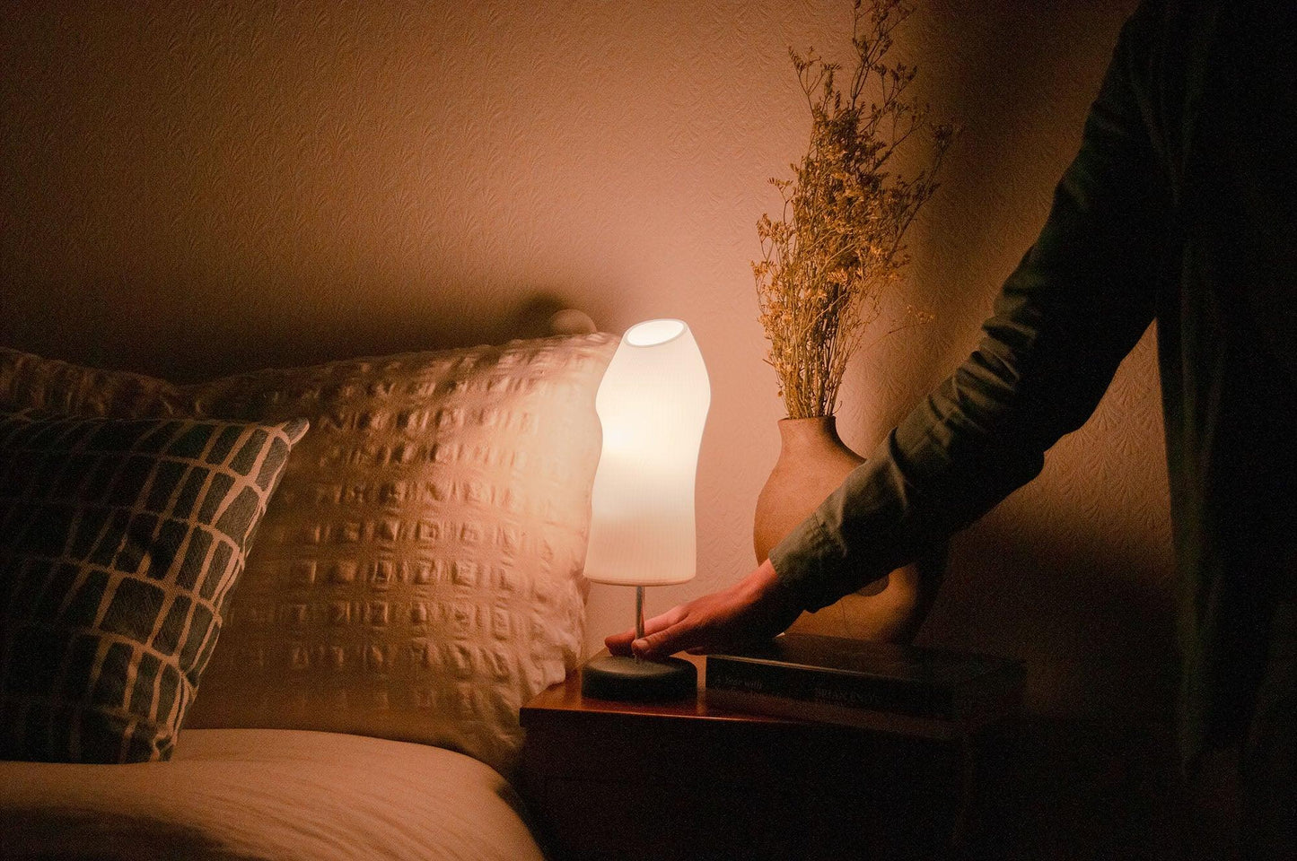 Ora bedside lamp lighting a dark bedroom positioned on a wooden chest of drawer