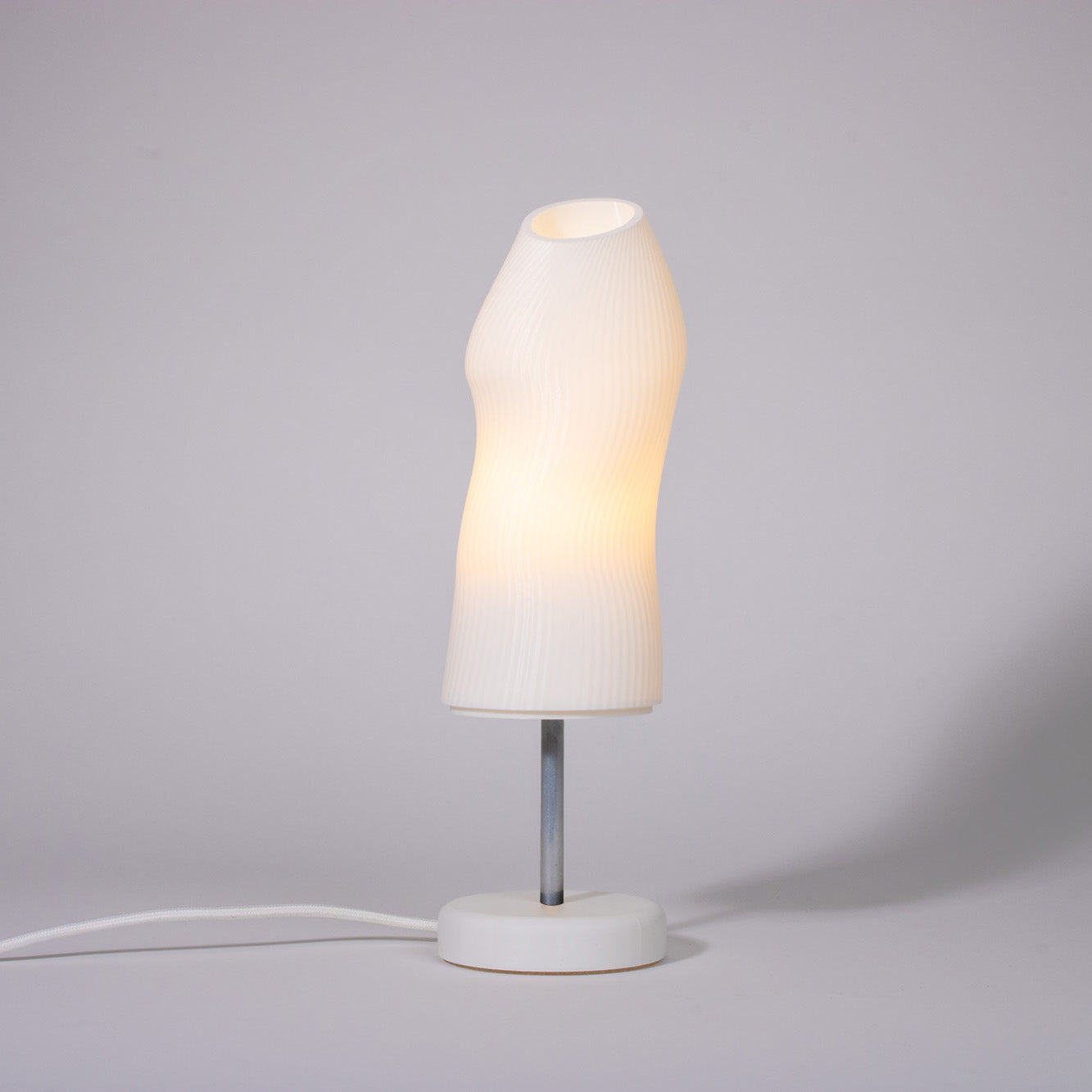 Ora white sculptural table lamp with chrome rod photographed against a white background